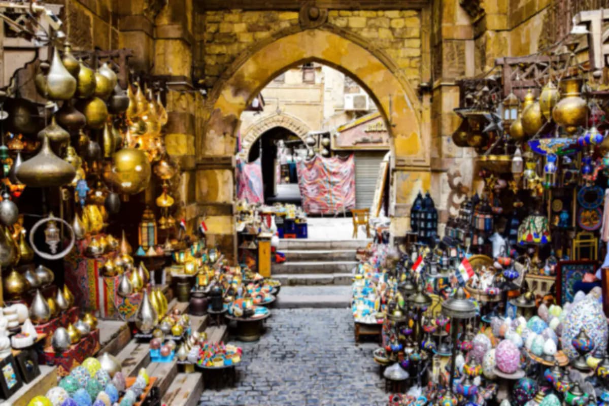 Brass lamps, glass lanterns and crafts for sale on both sides of a stone arch in a bazaar in Cairo