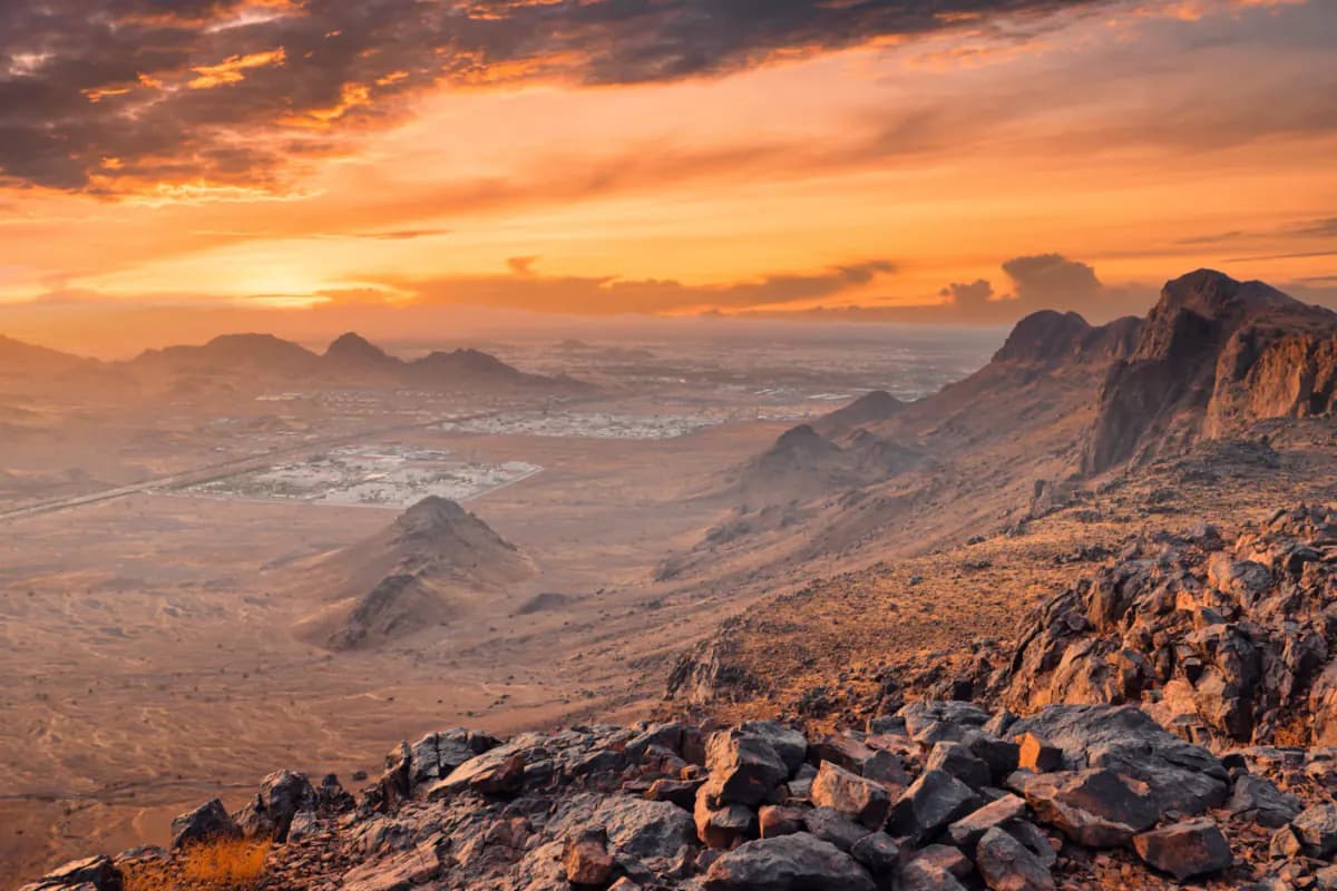 Rocky hills above Madinah at sunset, with the city spread across the plain below